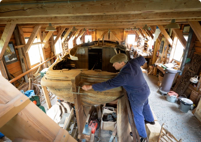Boat builder working on wooden vessel